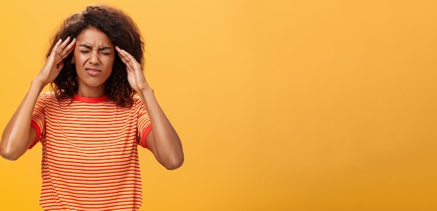 Free photo woman cannot recall important information looking intense trying concetrate under pressure feeling tensed touching temples closing eyes while thinking hard posing against orange background