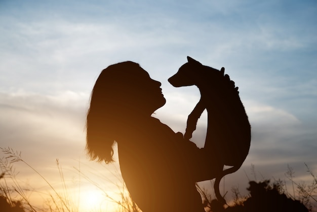 Woman carry her pet and hugging up to the sky.