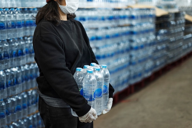 Free Photo woman carrying drinking waters with gloved hands during coronavirus pandemic