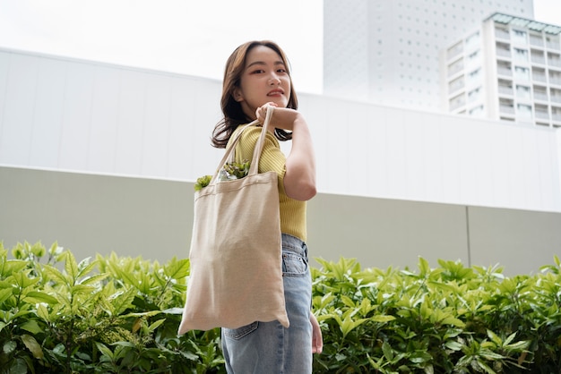 Free photo woman carrying groceries in tote bag medium shot