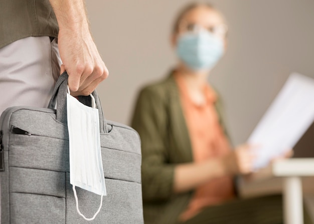 Free photo woman carrying laptop bag and face mask