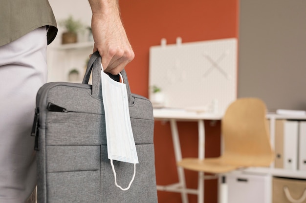 Free photo woman carrying laptop bag and face mask