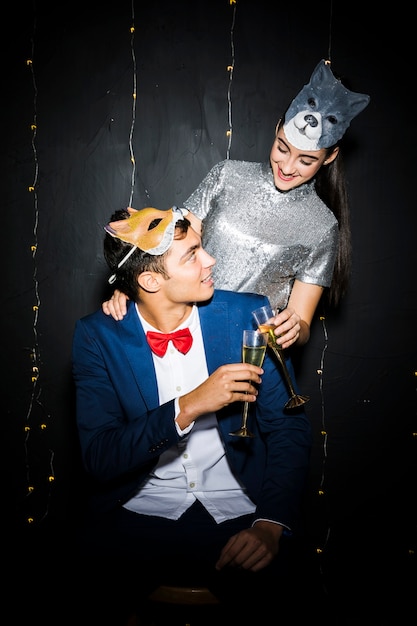 Woman in cat mask hugging man in fox mask and clinging glasses 