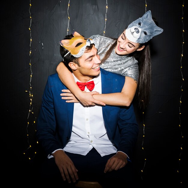 Woman in cat mask hugging man in fox mask