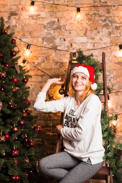 Woman on chair next to christmas tree