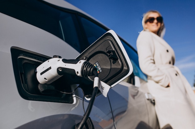 Woman charging electro car by her house