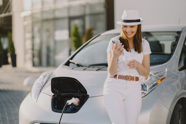 Woman charging electro car at the electric gas station