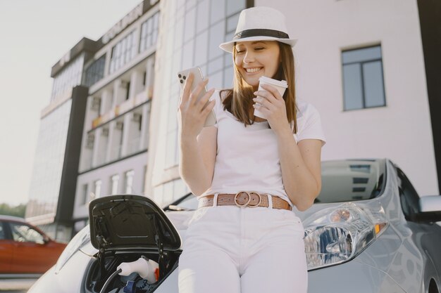 Woman charging electro car at the electric gas station