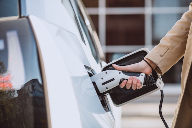 Woman charging electro car at the electric gas station