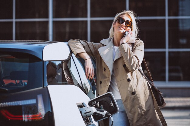 Woman charging electro car at the electric gas station