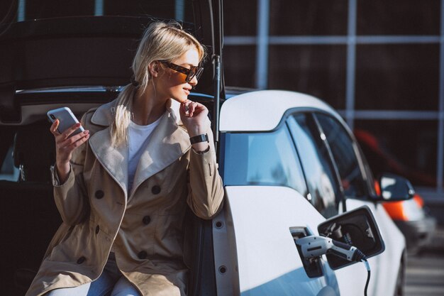 Woman charging electro car at the electric gas station