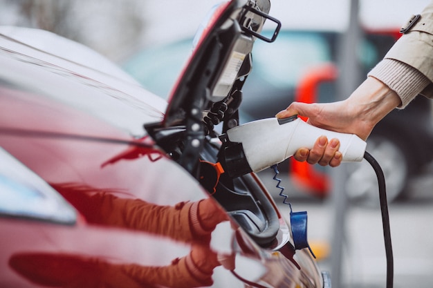 Woman charging electro car at the electric gas station