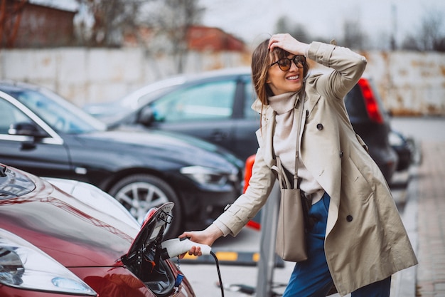 Woman charging electro car at the electric gas station