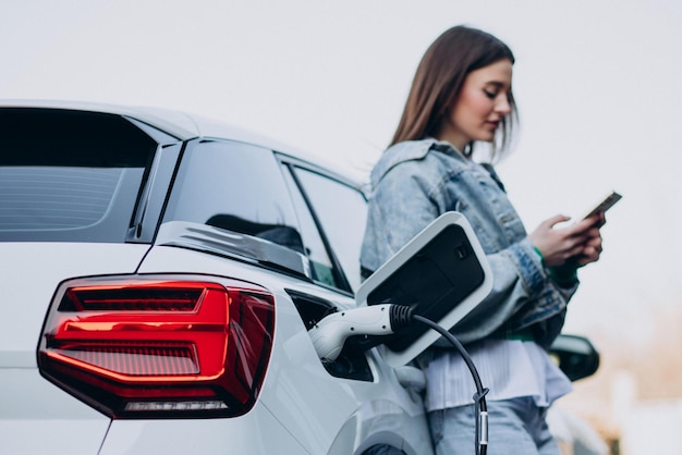 Free photo woman charging her electric car with charging pistol