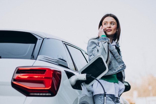 Woman charging her electric car with charging pistol