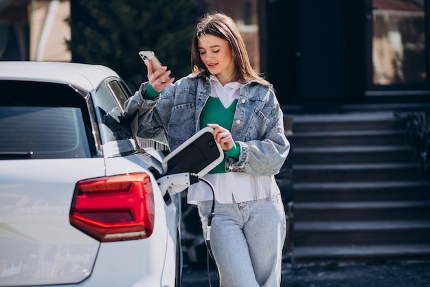 Free photo woman charging her electric car with charging pistol