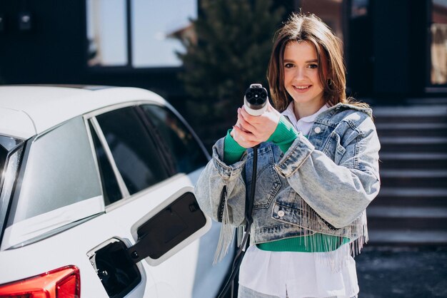 Woman charging her electric car with charging pistol