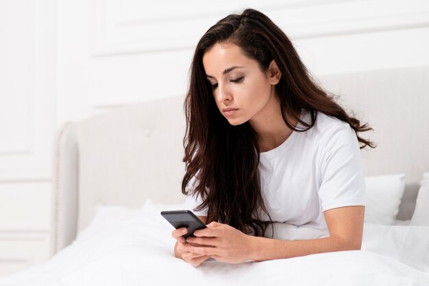 Woman checking her phone after waking up