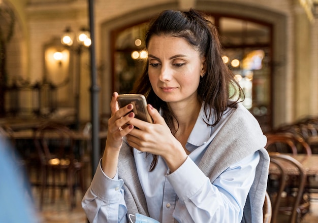 Free photo woman checking her phone at the restaurant