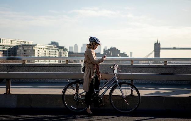 Free photo woman checking her smartphone and sitting on her bike