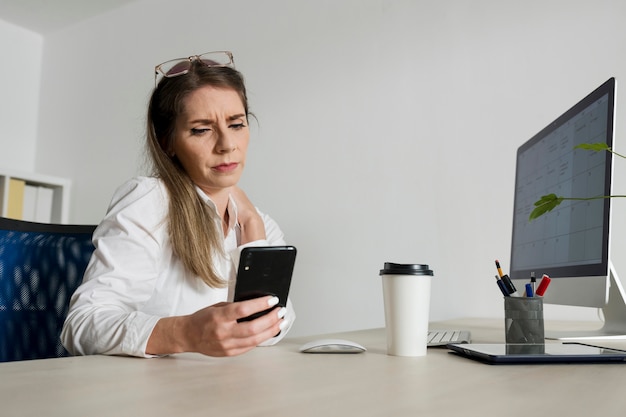 Free photo woman checking her smartphone at work