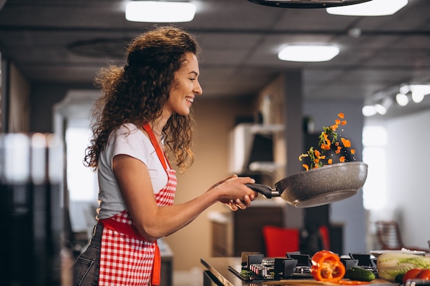 Woman chef cooking vegetables in pan