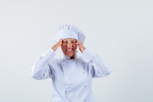 woman chef rubbing her temple in white uniform and looking stressful