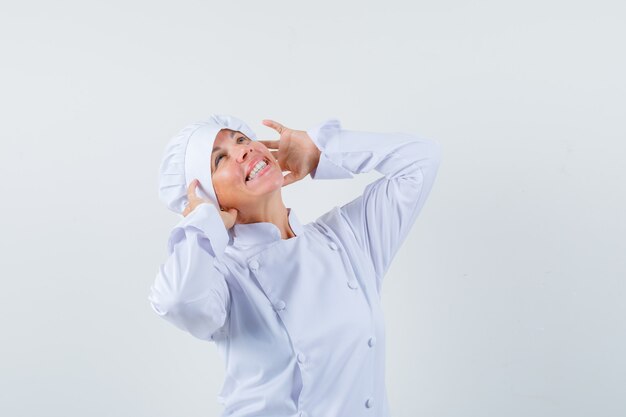 woman chef in white uniform pretending to use headphones and looking delighted