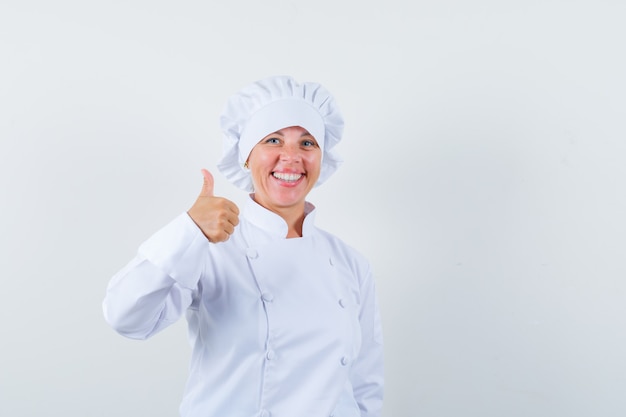 woman chef in white uniform showing thumb up and looking merry