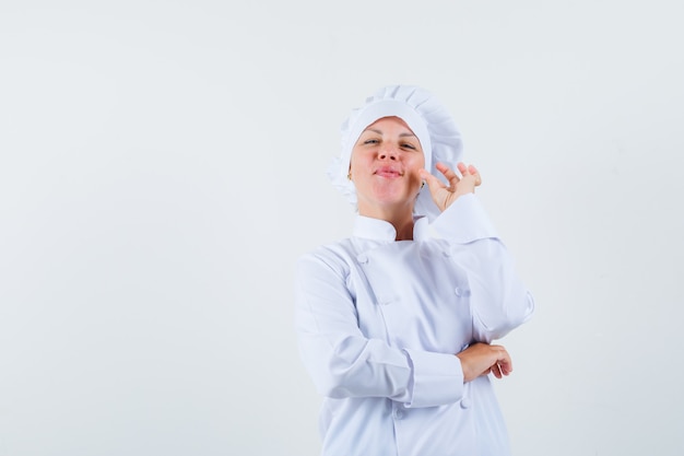 woman chef in white uniform showing zip gesture and looking assured space for text