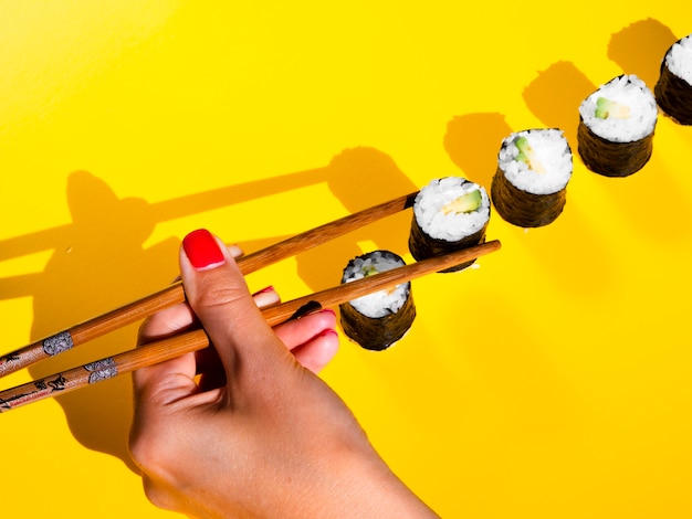 Woman choosing a nigiri roll from a yellow table