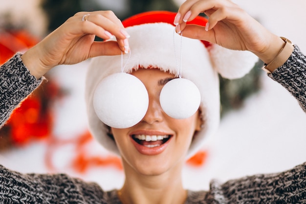 Woman on Christmas holding christmas tree toys in front of her eyes