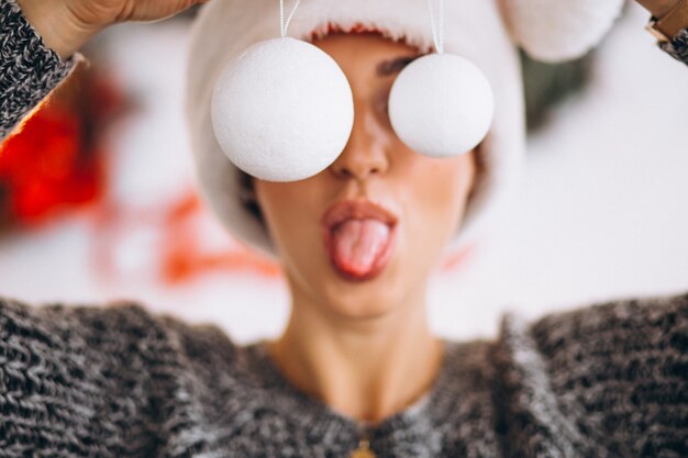 Woman on Christmas holding christmas tree toys in front of her eyes