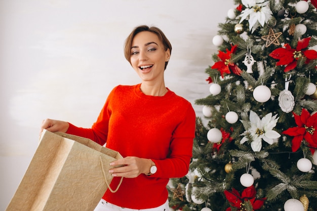 Free photo woman on christmas with gifts by christmas tree