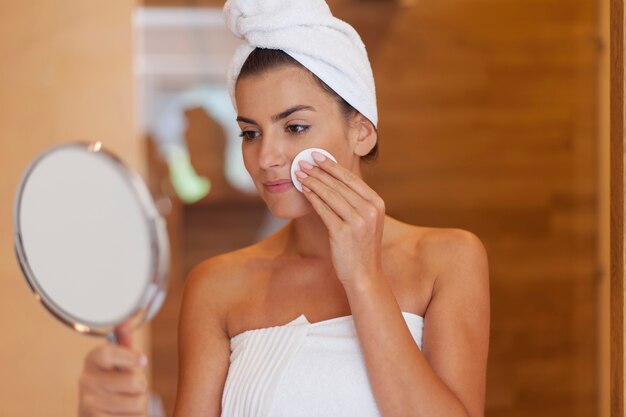 Woman cleaning face in bathroom