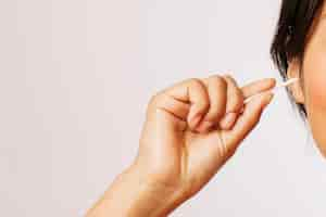 Free photo woman cleaning her ears with cotton swabs