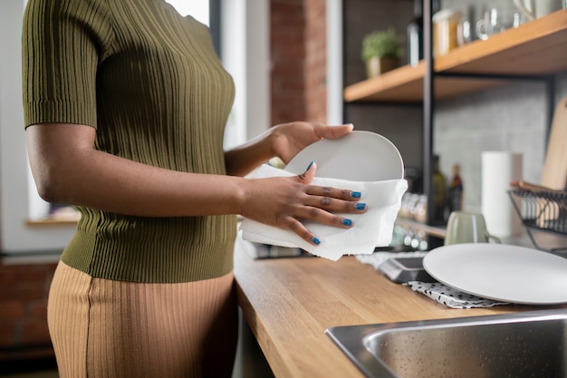 Woman cleaning plate in kitchen