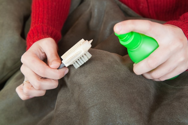 Woman cleaning a sheepskin with whisk broom