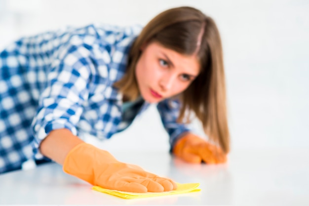 Woman cleaning white surface of the yellow napkin