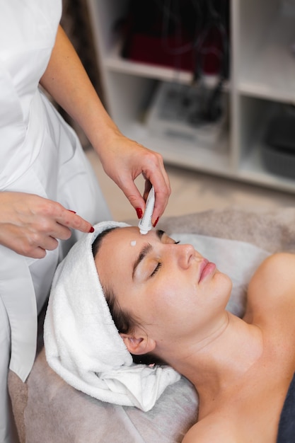 Woman client in salon receiving manual facial massage from beautician