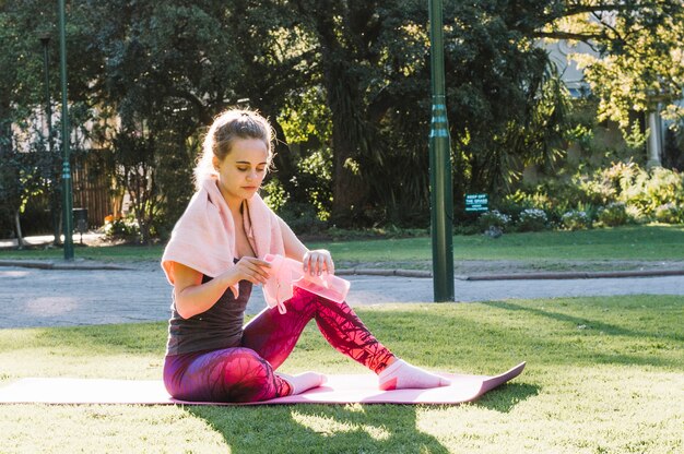 Woman closing water bottle on stretching mat