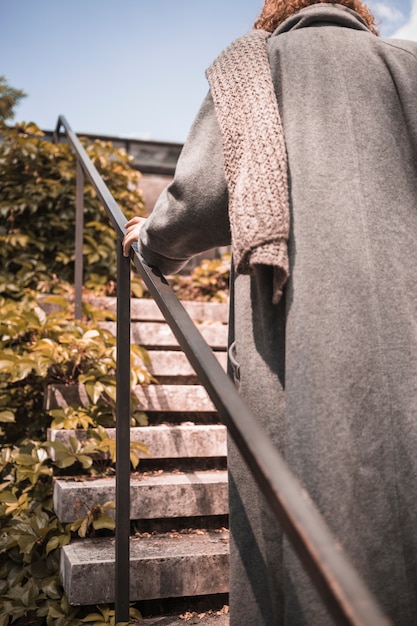 Free photo woman in coat scaling on steps