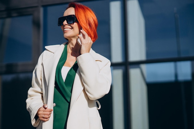 Free Photo woman in coat using phone outside the street