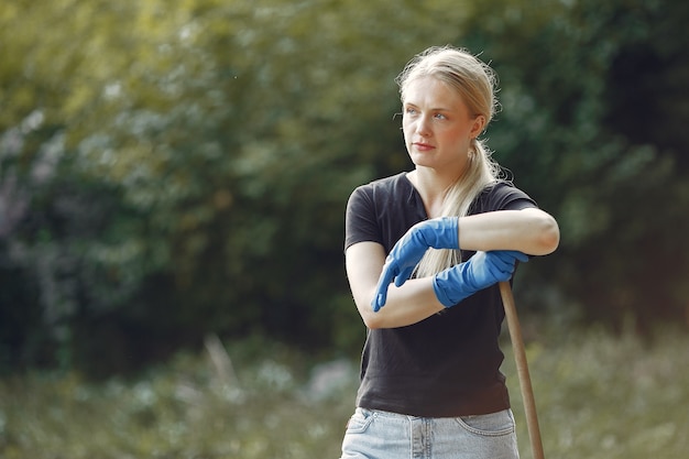 Woman collects leaves and cleans the park