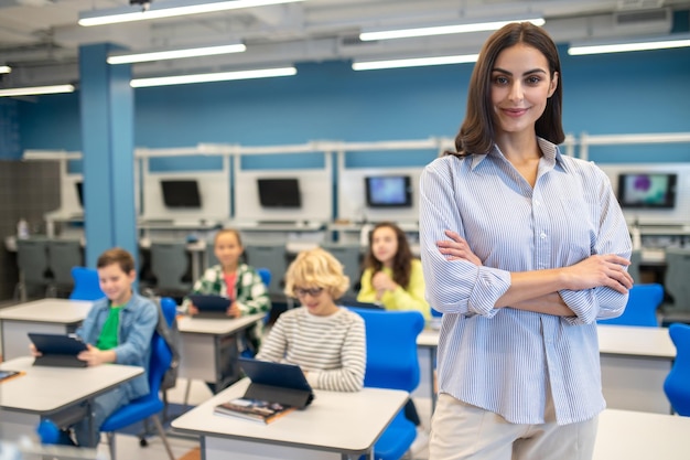 Free photo woman confidently looking at camera and students sitting behind