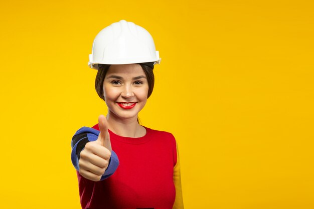 Woman in construction helmet shows thumbs up