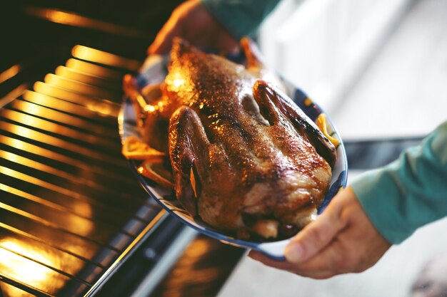 Woman cooking duck with vegetables and puting it from oven.