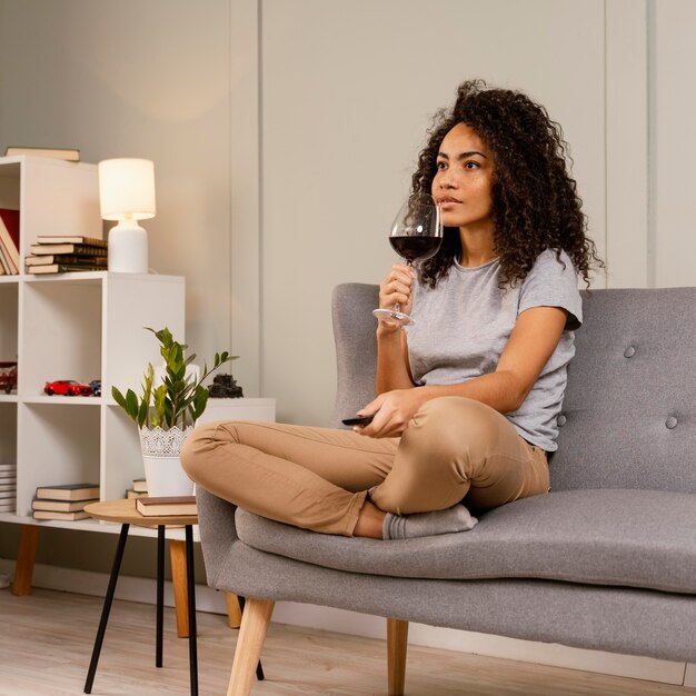 Woman on couch watching tv and drinking wine