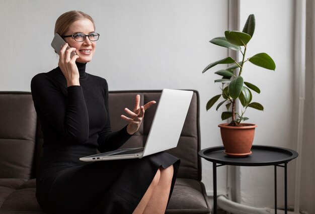 Woman on couch with laptop and phone