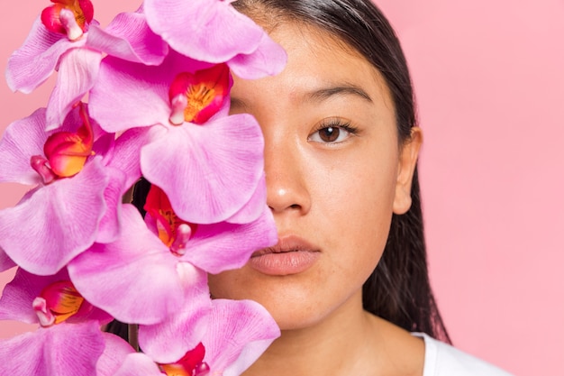 Free photo woman covering her face with orchid petals